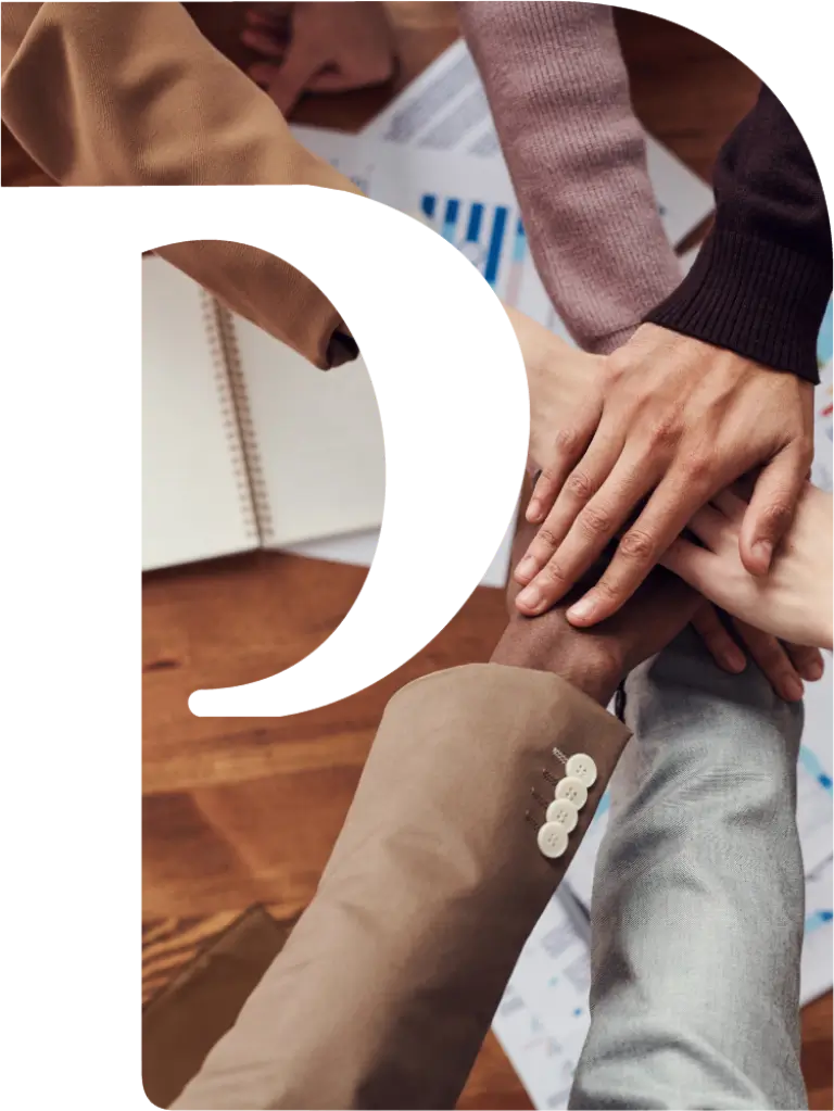 A group of people demonstrating unity by putting their hands together on a table as a symbol of effective business management.