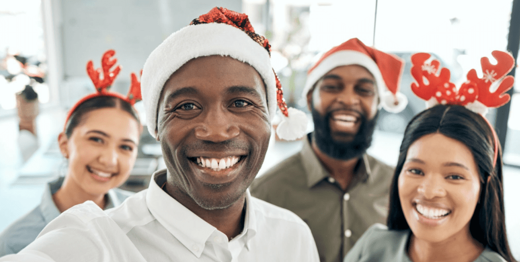 A group of people in santa hats taking a selfie while exchanging holiday greetings.