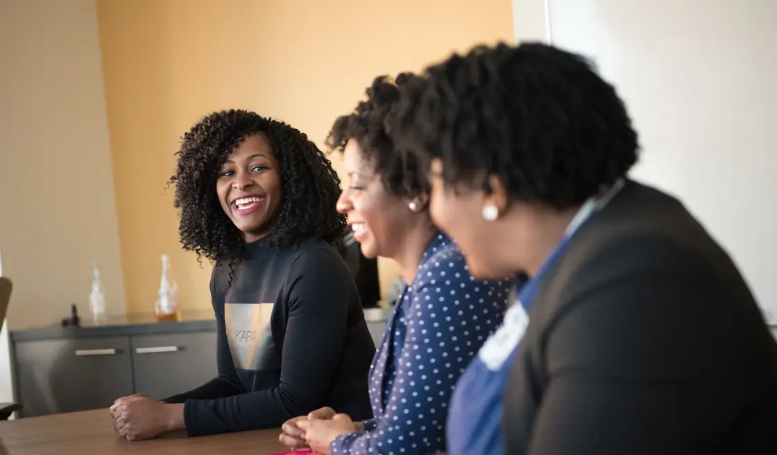 Three smiling women at a table.