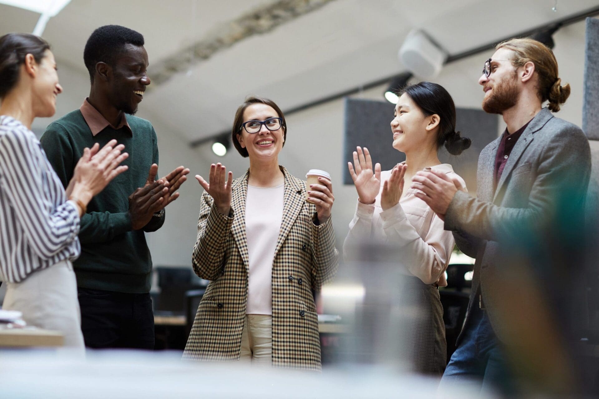 Four colleagues happily celebrate a success in an office meeting.