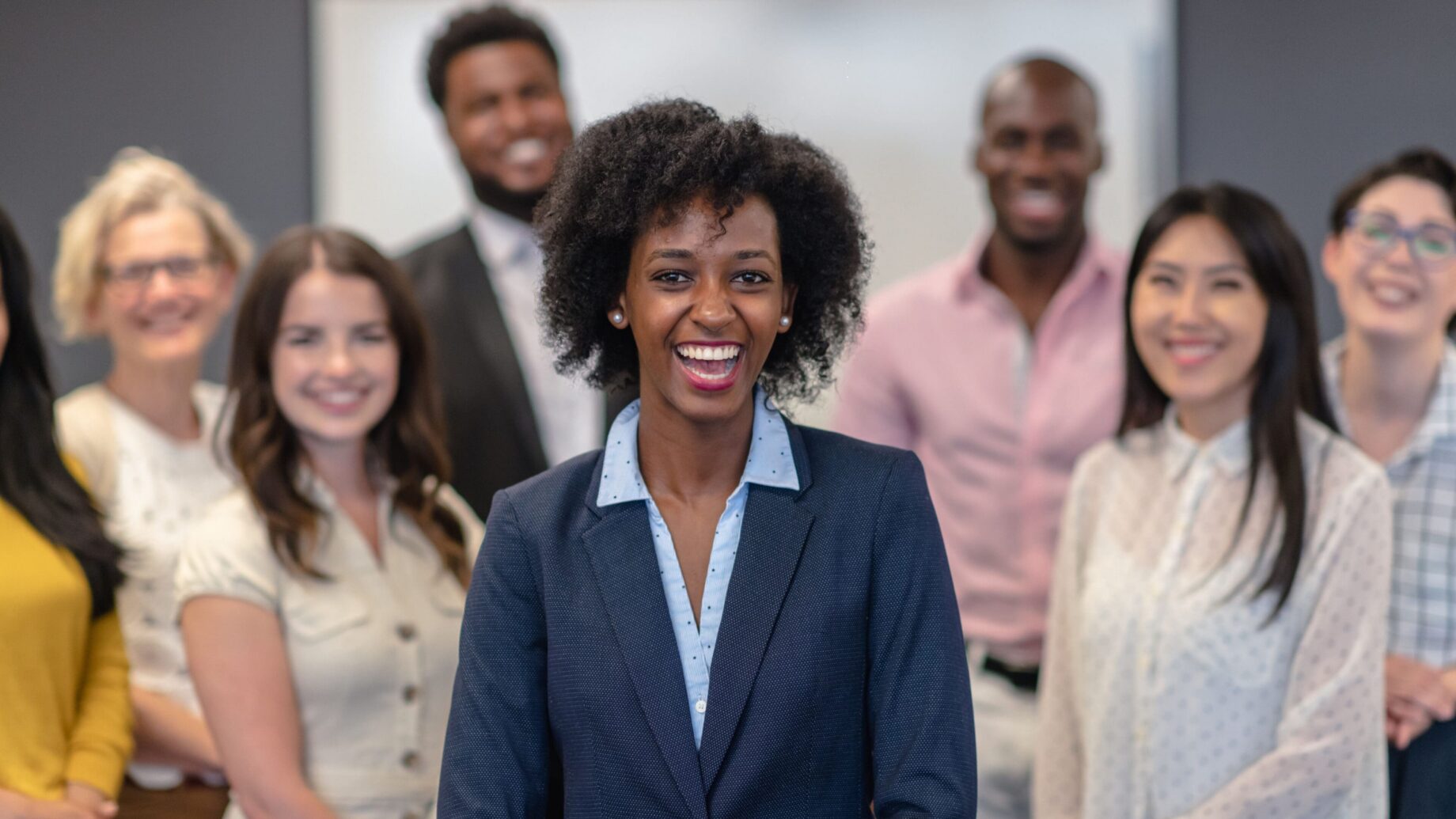 Smiling professional woman with colleagues in the background.