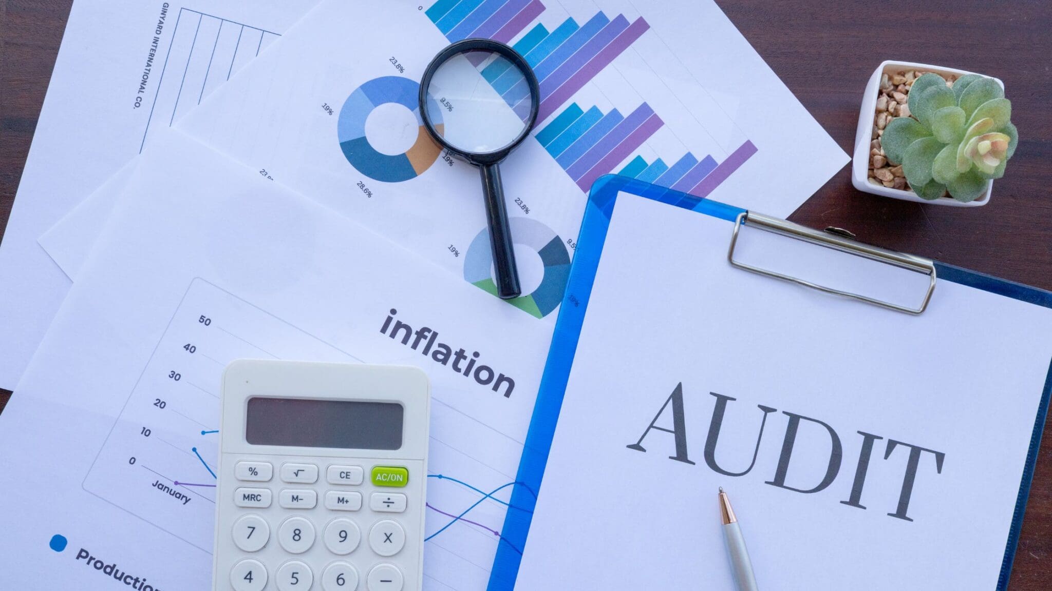 Magnifying glass on charts and documents about inflation and audit.