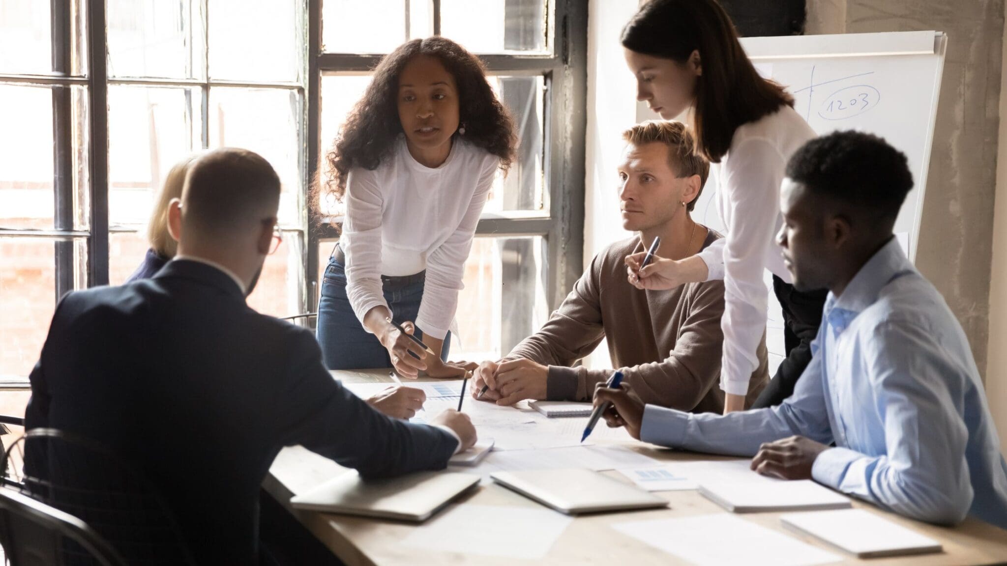 Team collaborating actively around a table in a bright office.