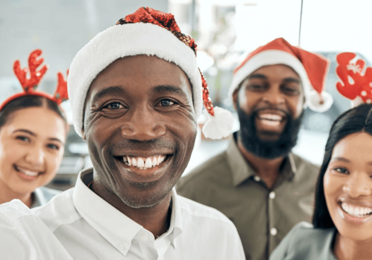 A group of people in santa hats taking a selfie while exchanging holiday greetings.